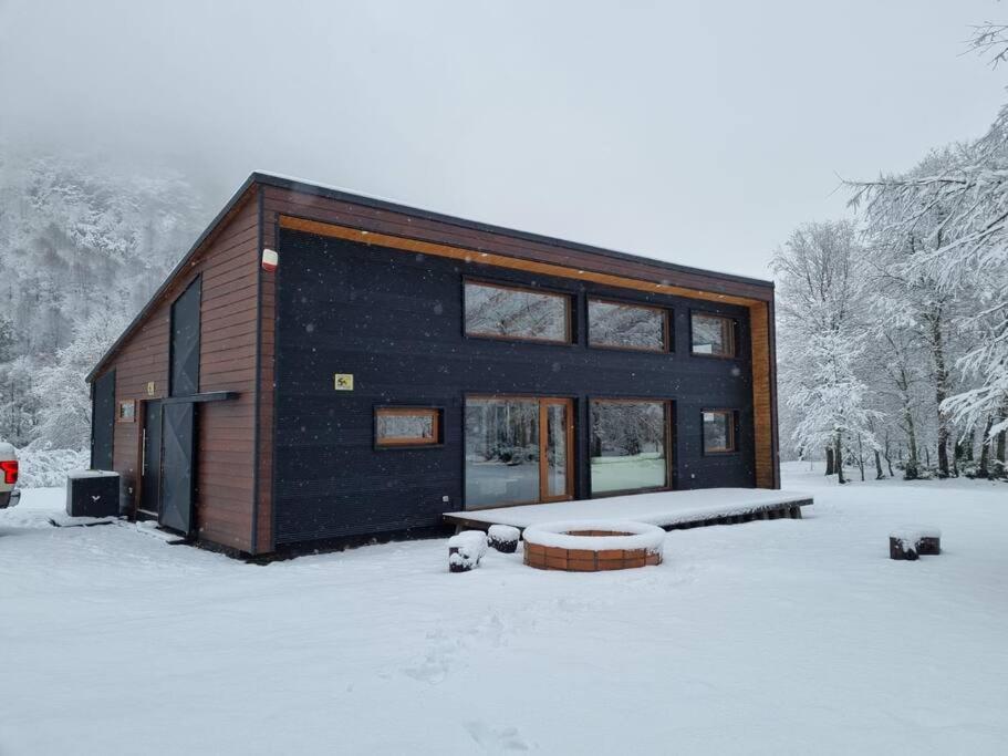 una casa negra en la nieve con un banco en Casa Malalcahuello Corralco, en Malalcahuello