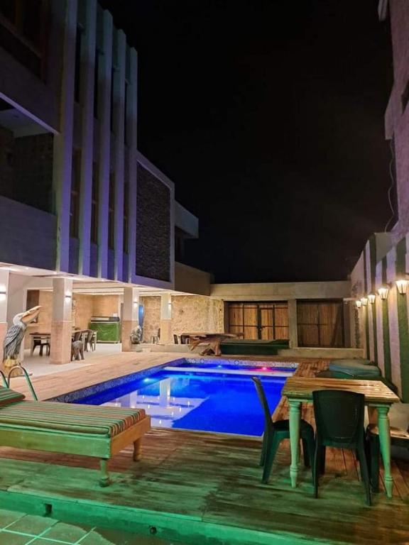 una piscina por la noche con mesa y sillas en Cabaña Maria, en Santa Marta