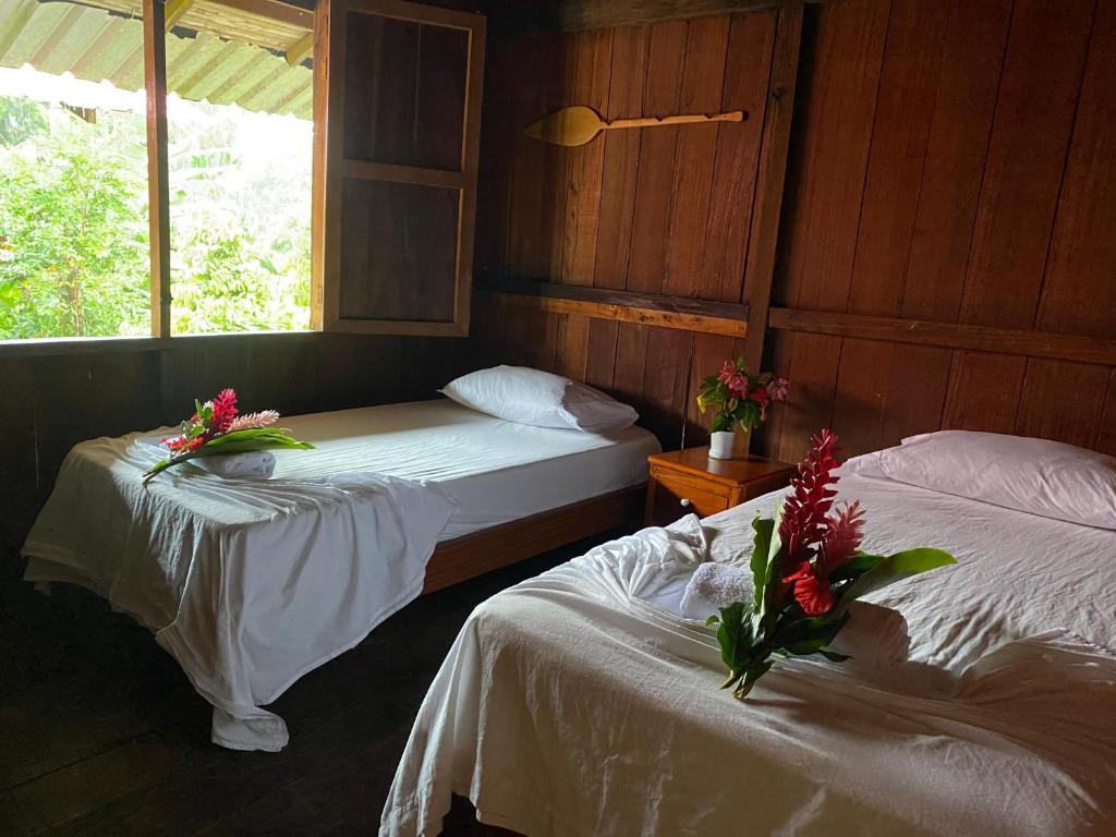 two beds in a room with flowers on them at Cabañas Iracas del Mar in Nuquí