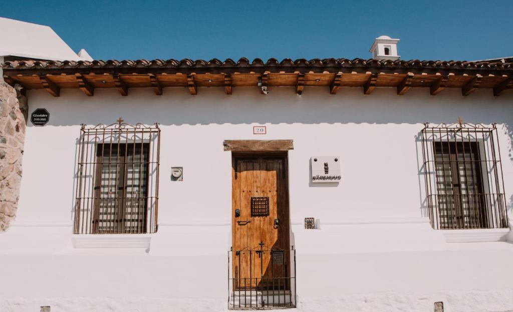a white building with a wooden door and two windows at Bärehuus Boutique Hotel in Antigua Guatemala