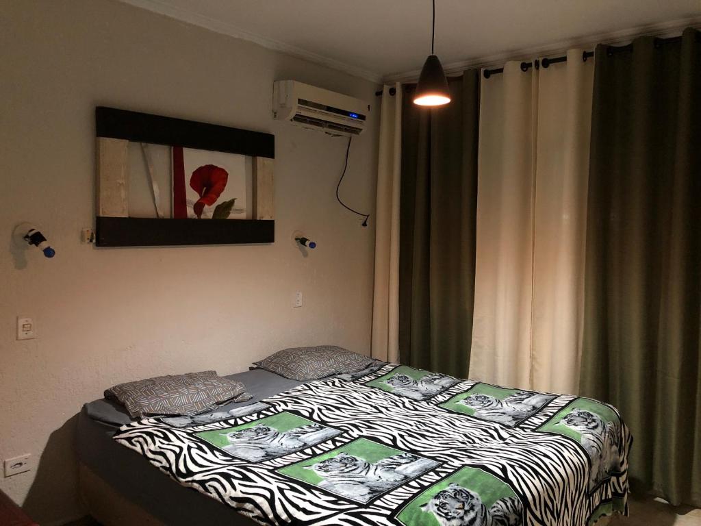 a bedroom with a bed with a zebra blanket on it at Quarto Duplo Costa brava in Guarujá