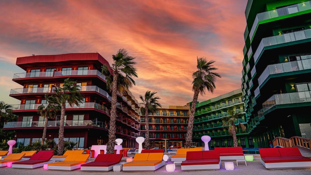 um edifício com palmeiras e cadeiras em frente a um edifício em voco Monaco Dubai, an IHG Hotel, Adults Only, World Islands no Dubai