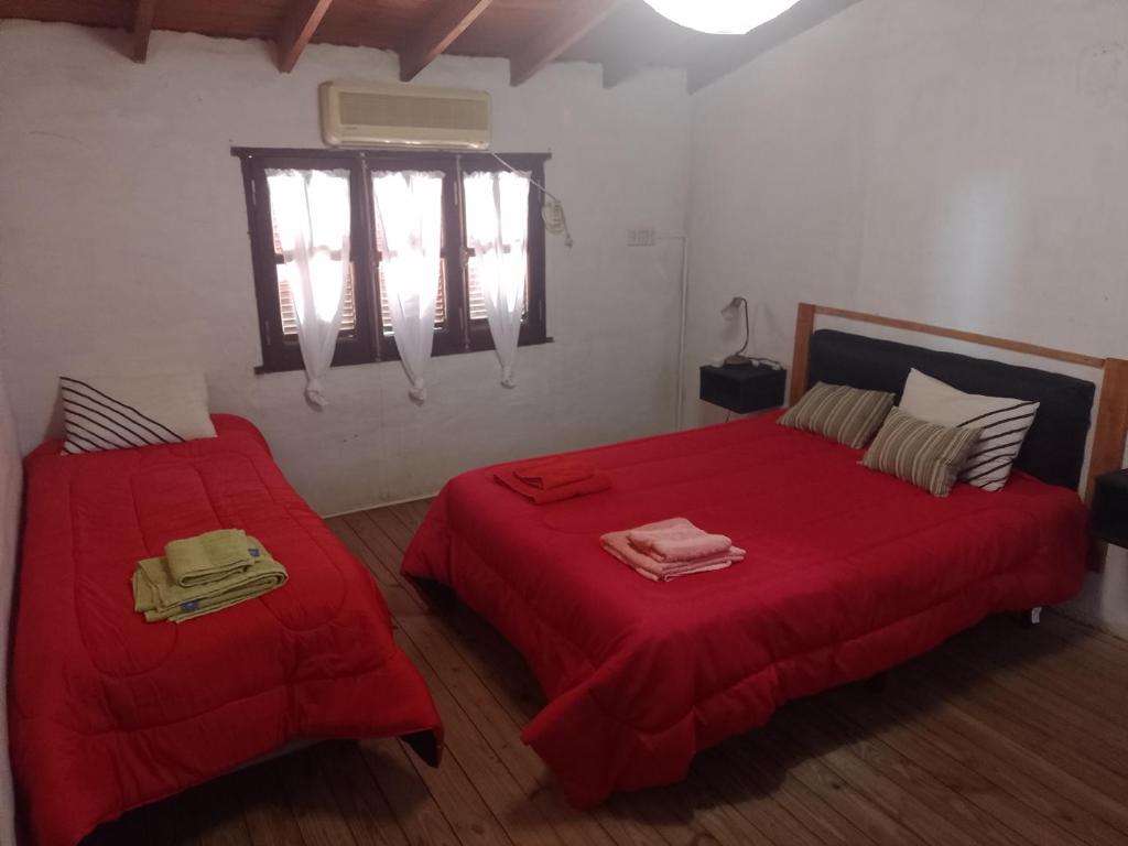 um quarto com 2 camas com lençóis vermelhos e uma janela em Alojamiento por día Merlo San Luis em Merlo