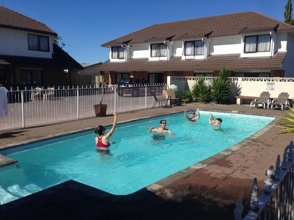 3 Leute spielen in einem Schwimmbad in der Unterkunft Palm City Motor Inn in Napier