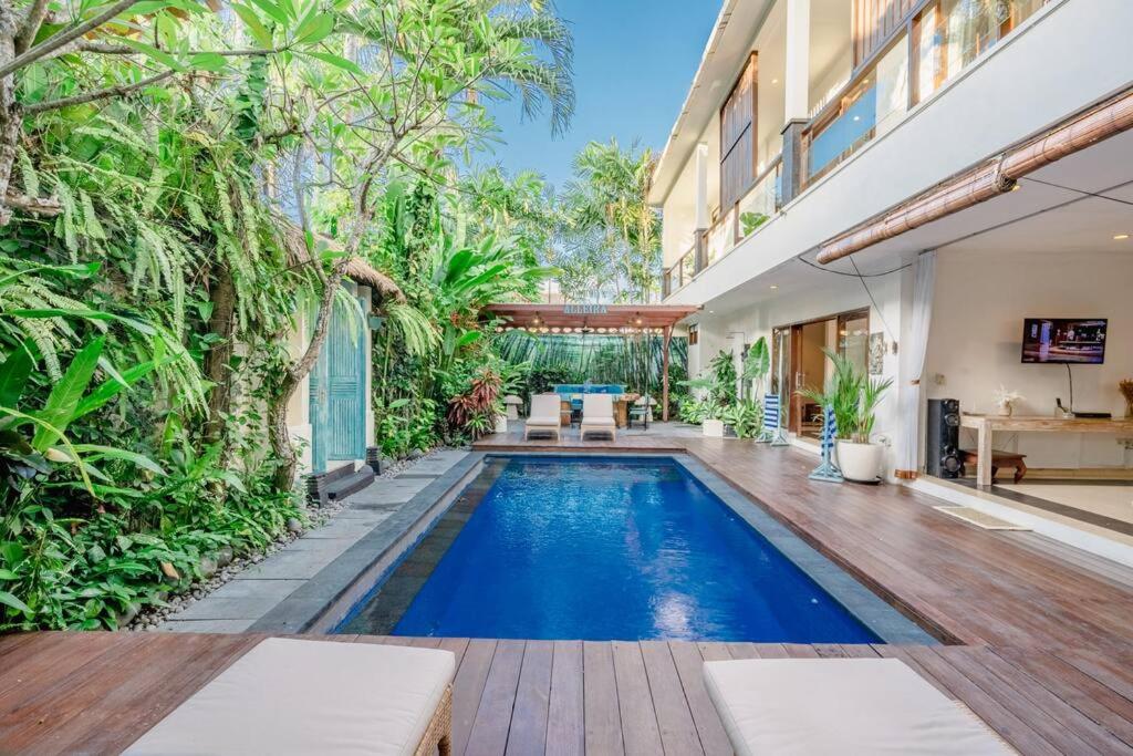 an outdoor swimming pool with a wooden deck and a house at 5 Bedroom Villa in Centre Location of Seminyak in Seminyak