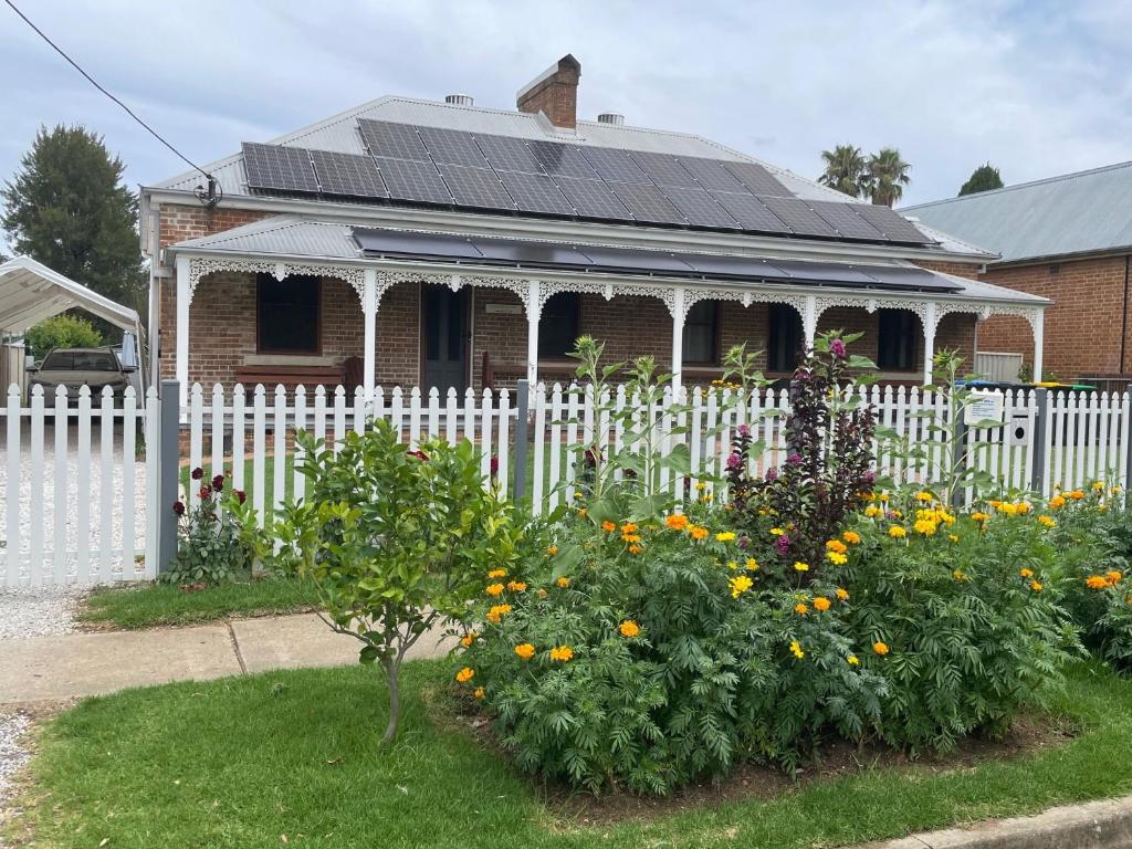 a white fence in front of a house with flowers at A Homestead on Market in Mudgee