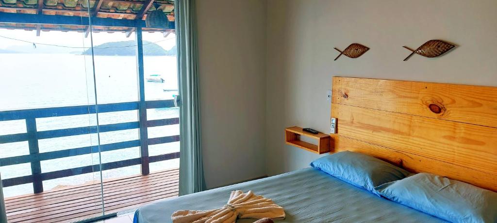 sypialnia z łóżkiem z drewnianym zagłówkiem i oknem w obiekcie Pousada Gabriel w mieście Praia de Araçatiba