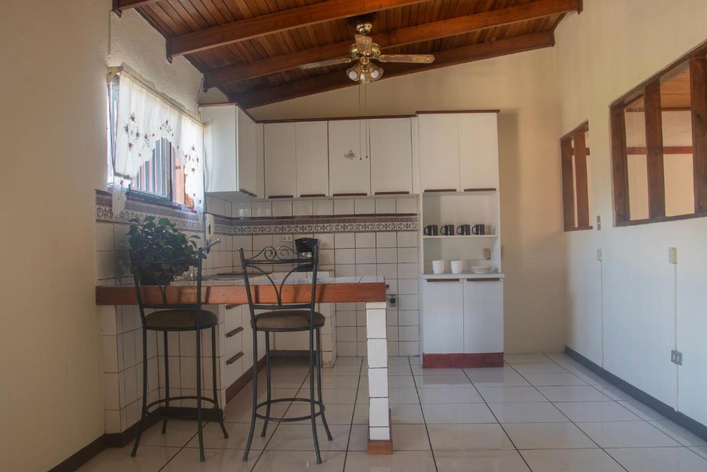 a kitchen with white cabinets and a counter with stools at Casa Calas in Alajuela City