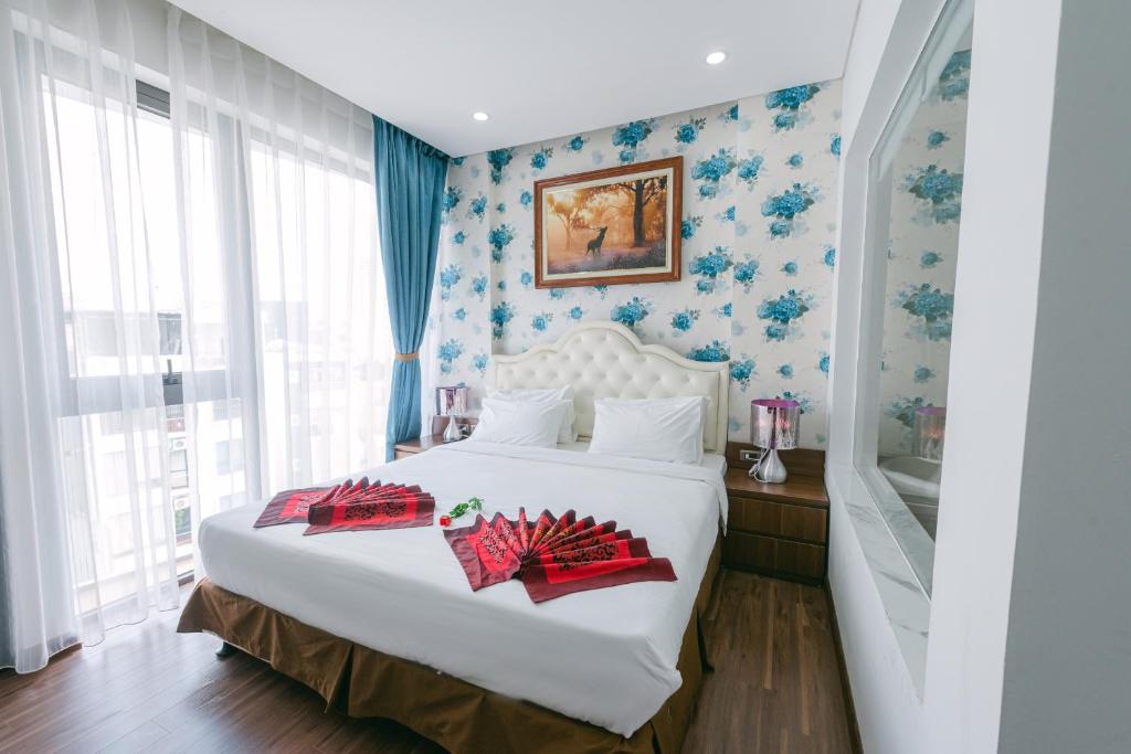 um quarto com uma cama branca e papel de parede floral azul em New Century Hotel Cau Giay em Hanói