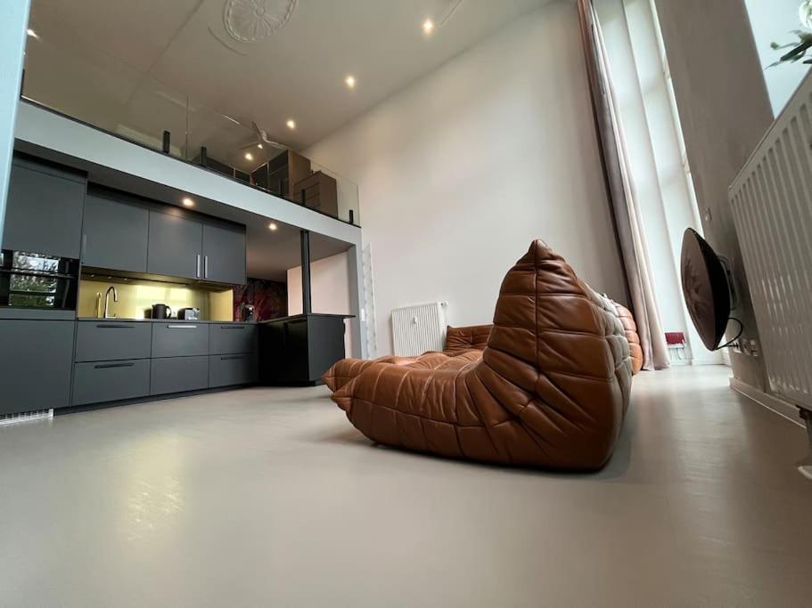 マクデブルクにあるDuplex Loft mit Gartenのキッチンの床に置かれた茶色の革張りのソファ