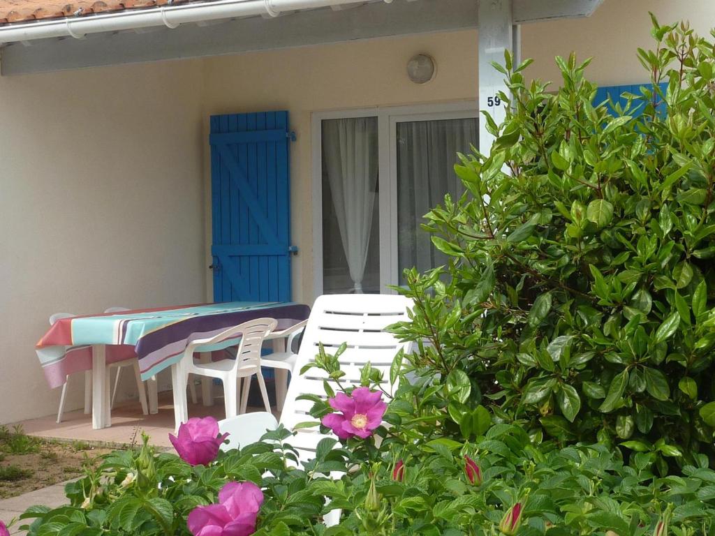 eine Terrasse mit einem Tisch, Stühlen und Blumen in der Unterkunft Maison Bretignolles-sur-Mer, 1 pièce, 5 personnes - FR-1-231-295 in Brétignolles-sur-Mer