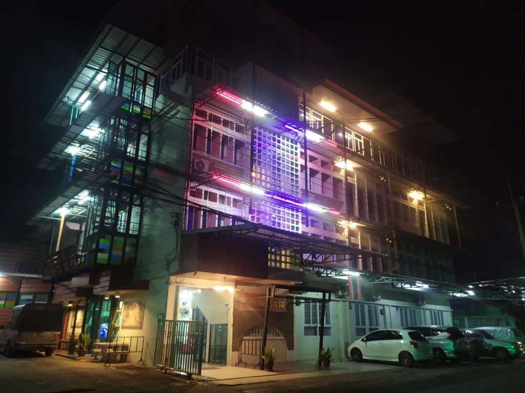 un edificio con coches aparcados delante de él por la noche en โรงแรมพรถวิล ศรีสะเกษ Sisaket PonTaWin Budget Inn, en Sisaket