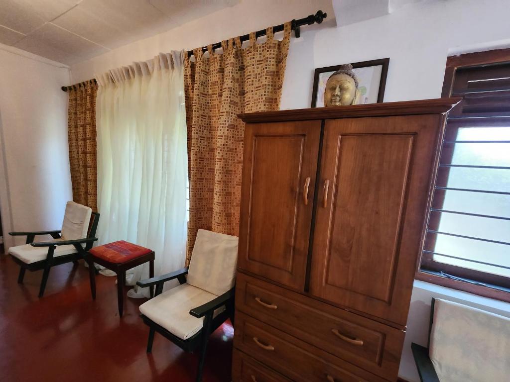 un soggiorno con armadio, sedie e finestra di Ruwanwali Resort a Anuradhapura