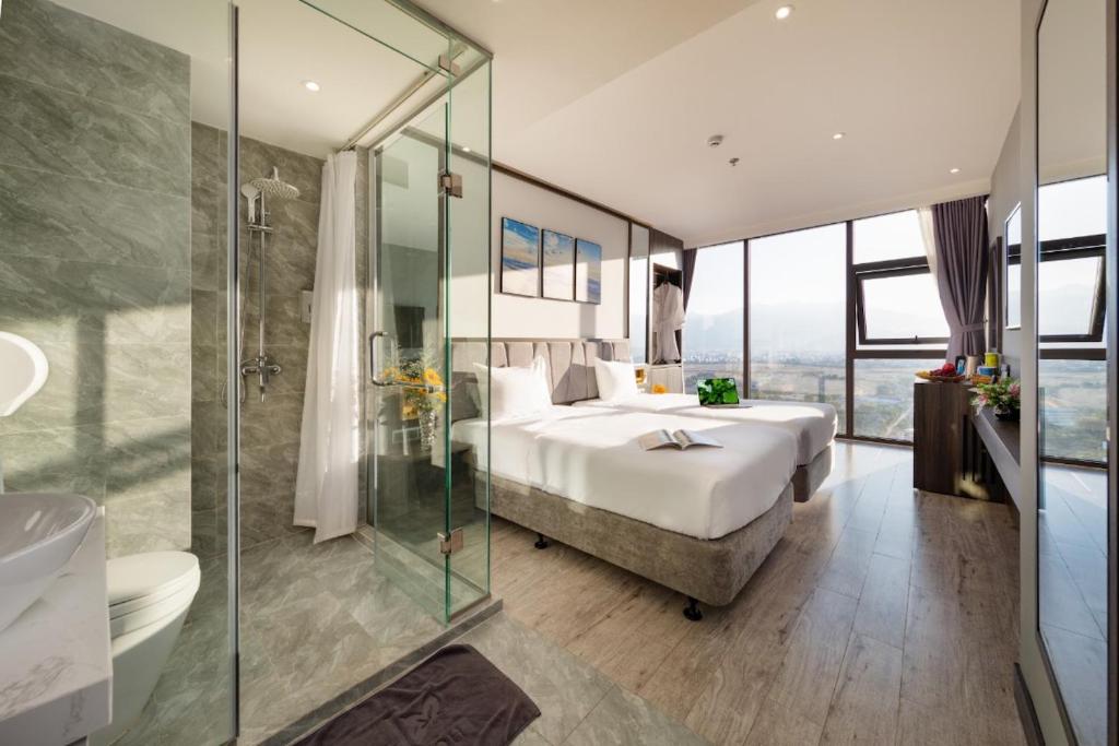 - une chambre avec un lit et une douche en verre dans l'établissement Ivy Hotel Nha Trang, à Nha Trang