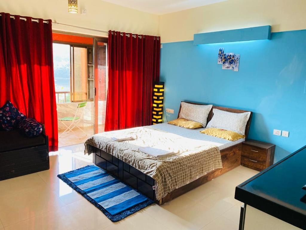 a bedroom with a bed with blue walls and red curtains at Lake View Lavish studio in Lavasa