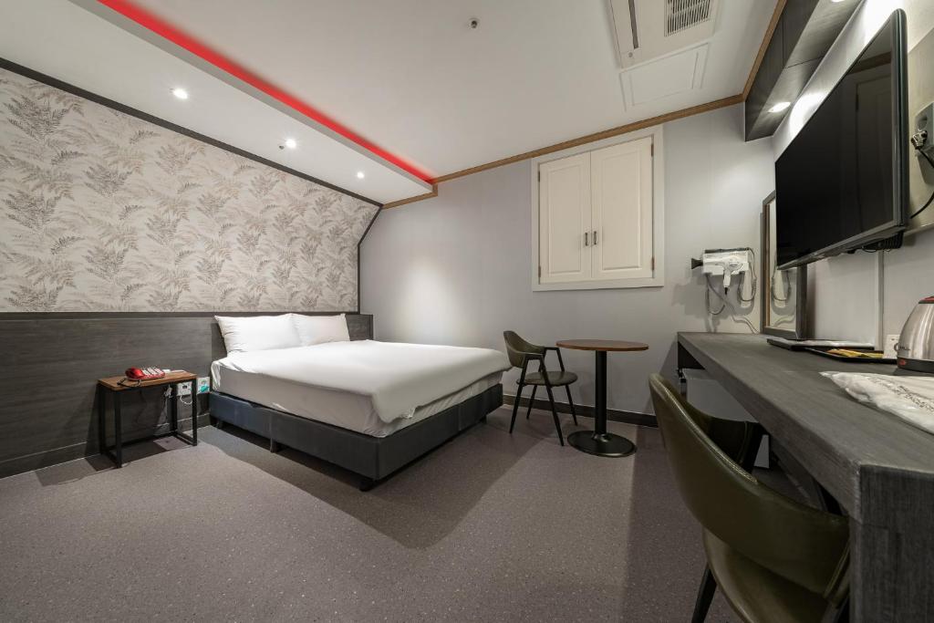 ソウルにあるSignature Tourist Hotelのベッドとキッチンのある小さな部屋