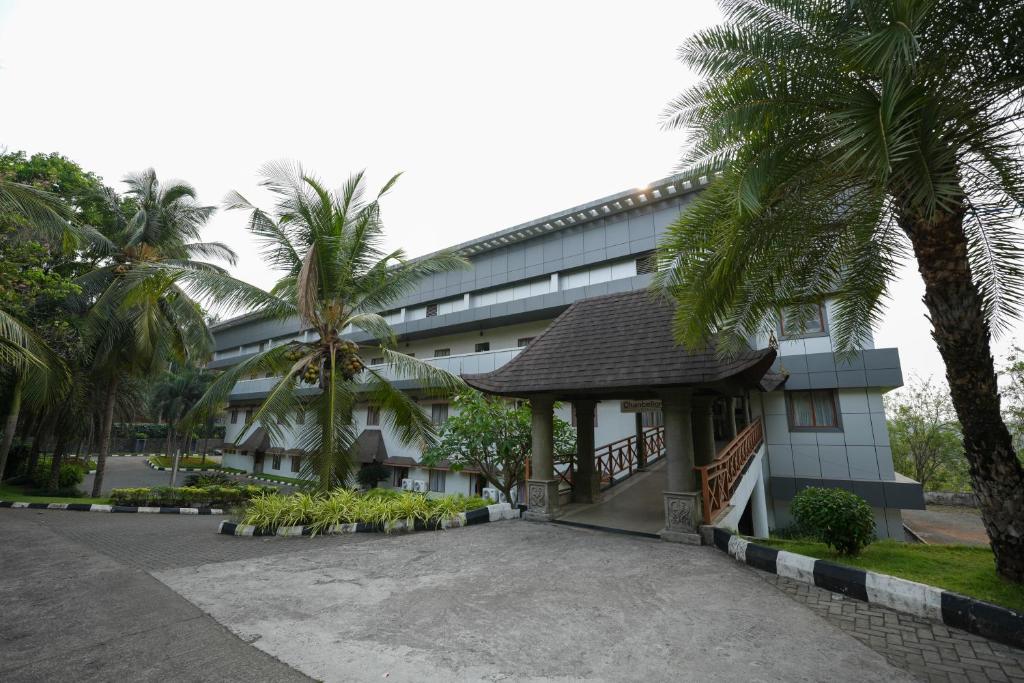 a large building with palm trees in front of it at Eco Garden Resort & Heritage Cheruthuruthy Thrissur in Cheruthuruthi