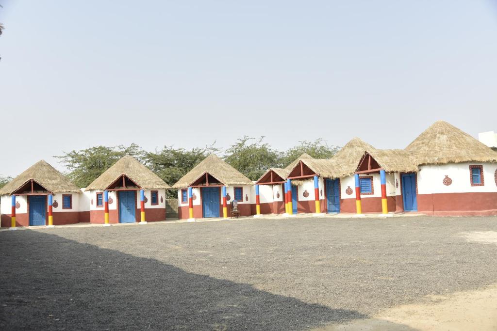 a row of colourful houses with thatched roofs at Rann Kutch Resort in Dhordo
