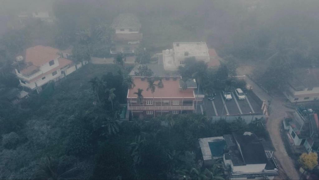 an aerial view of a house in the fog at Easy Inn Wayanad in Kaniyāmbetta