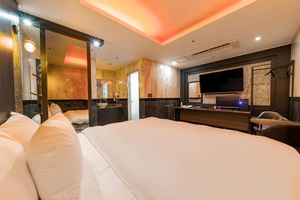 - une chambre avec un grand lit blanc et une télévision à écran plat dans l'établissement Hotel Signature, à Séoul