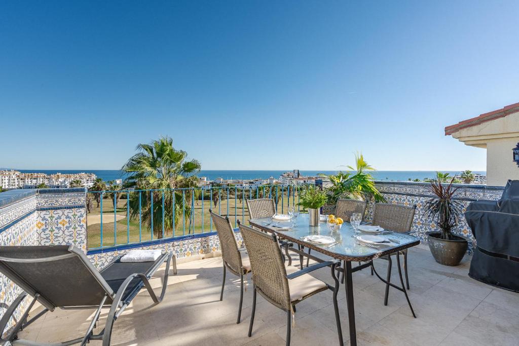 eine Terrasse mit Tisch und Stühlen und dem Meer in der Unterkunft 26 Front row penthouse golf and sea views Manilva Duquesa Andalusia in Manilva