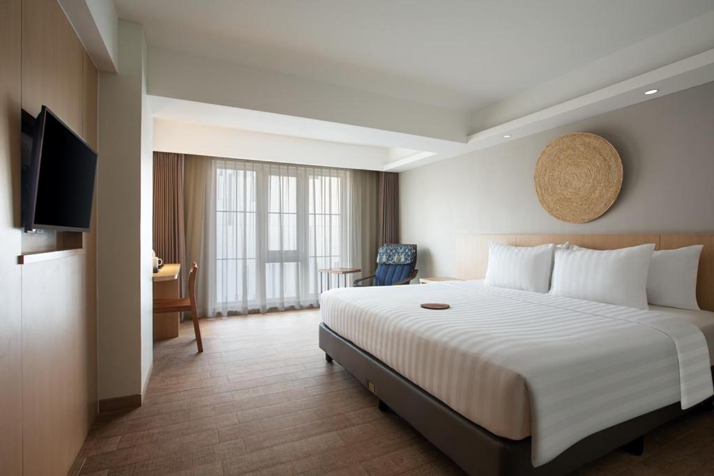 a hotel room with a large bed and a television at Aveta Hotel Malioboro in Yogyakarta