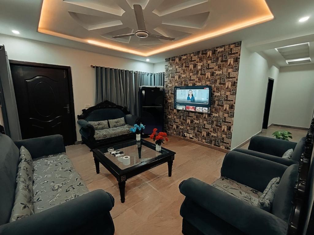 sala de estar con sofás y TV en la pared en Daily BASIS 3-BEDROOMS FAMILY APARTMENT, en Islamabad