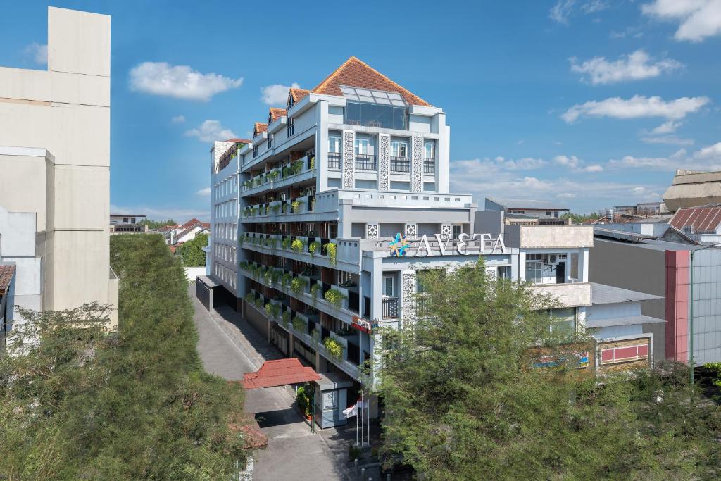 a tall white building with a balcony in a city at Aveta Hotel Malioboro in Yogyakarta
