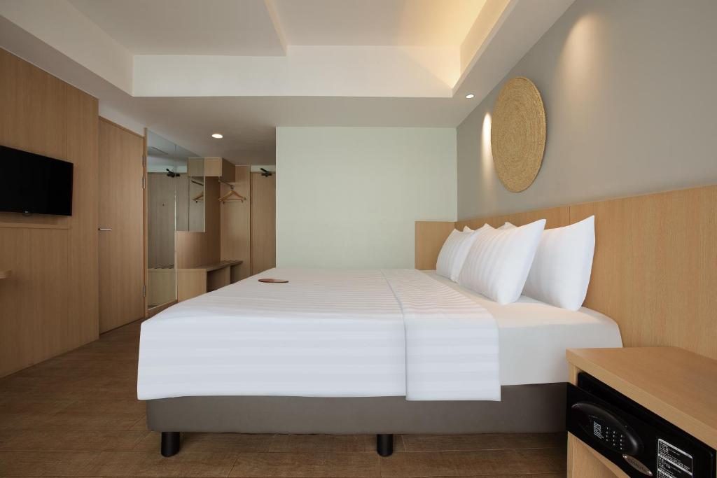 a bedroom with a large white bed and a television at Aveta Hotel Malioboro in Yogyakarta