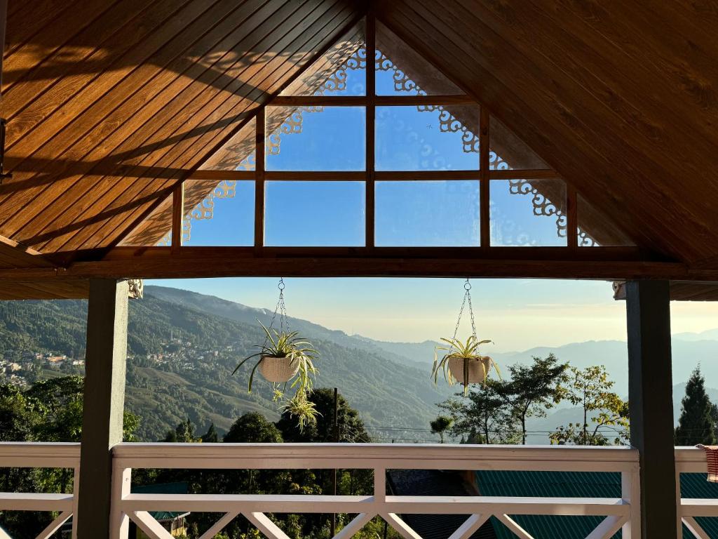 a window in a house with a view of the mountains at Pine Forest Retreat in Kurseong