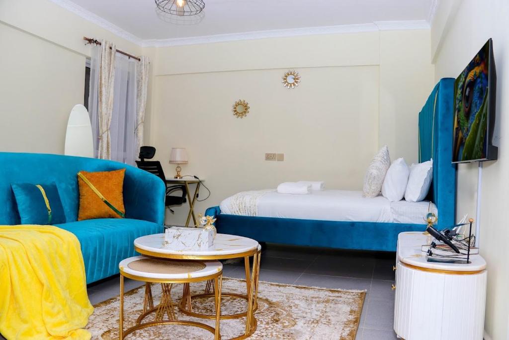 een woonkamer met een blauwe bank en een bed bij Epic Home By Edmor Suite in Nairobi