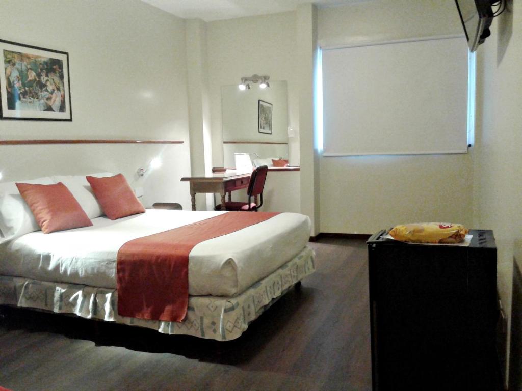 ブエノスアイレスにあるAlpino Hotelのベッド、テーブル、椅子付