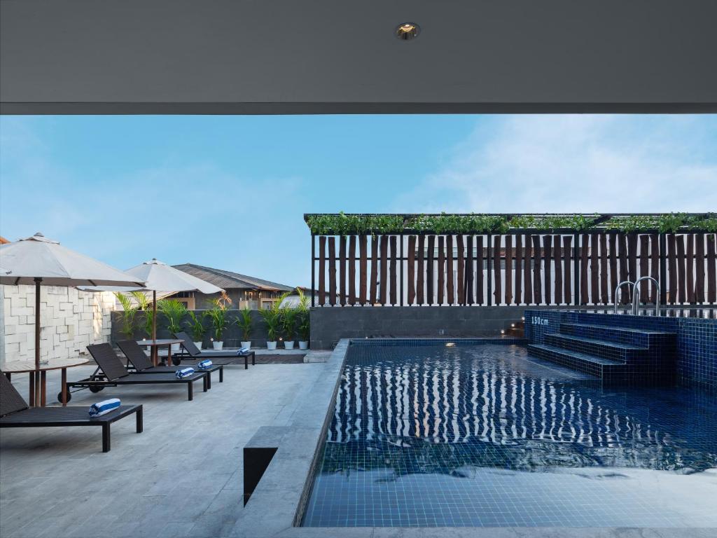 a swimming pool with lounge chairs and an umbrella at Aveta Hotel Malioboro in Yogyakarta