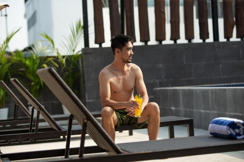 a man sitting on a chair next to a swimming pool at Aveta Hotel Malioboro in Yogyakarta