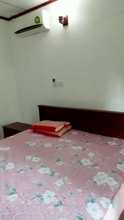 uma cama com uma colcha rosa com flores em Praveen villa em Beruwala