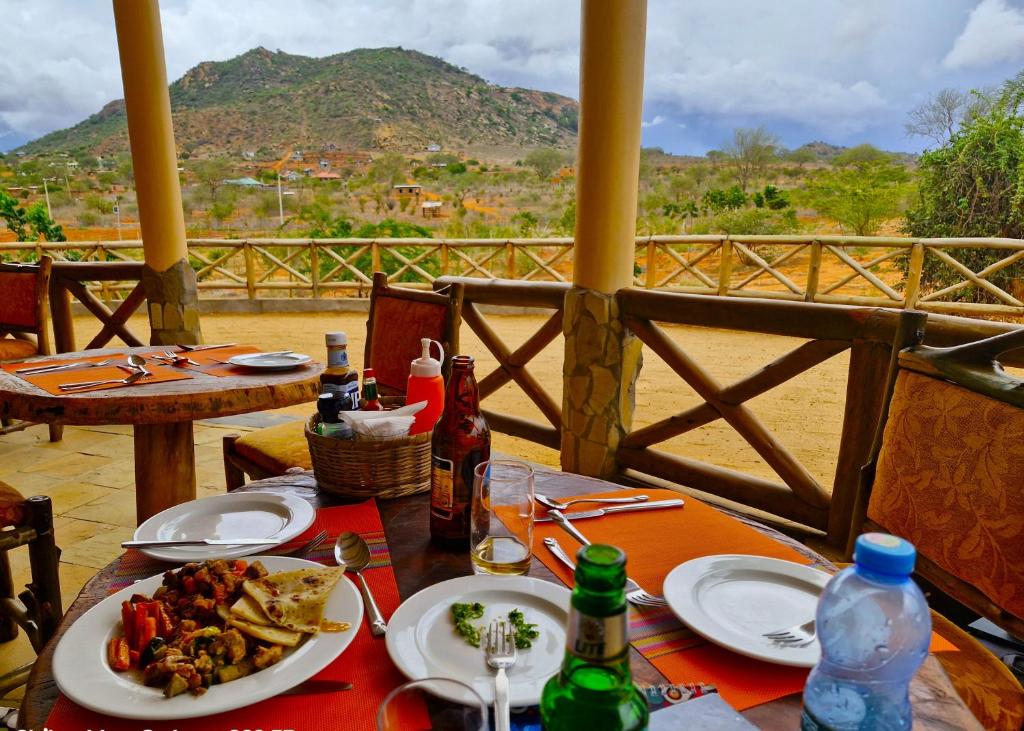 a table with plates of food and drinks on it at Boma Simba Safari Lodge in Voi