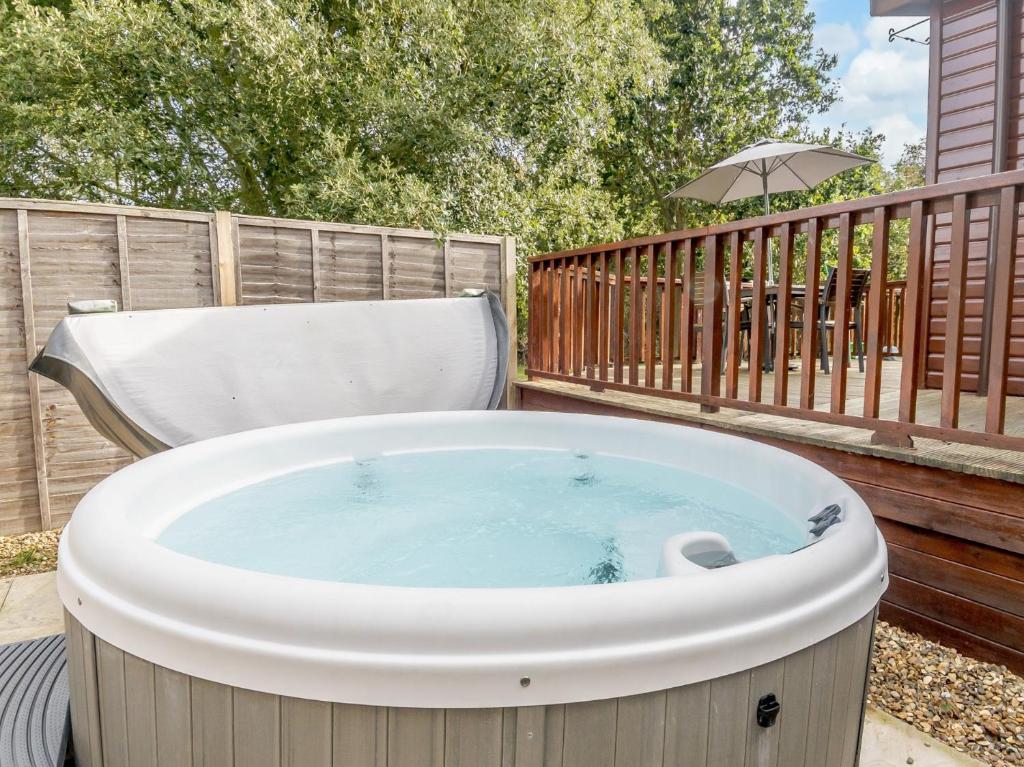 a hot tub on a deck with a chair at 2 Bed in Dunwich 85185 in Westleton