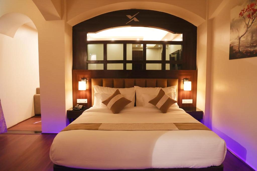 XCELSIOR HOTEL & SPA في شيلونغ: غرفة نوم مع سرير كبير مع أضواء أرجوانية