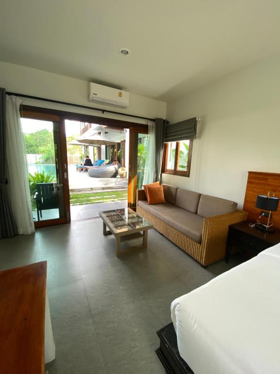 a bedroom with a bed and a couch and a table at Baan Yaimai Boutique Samui in Bophut