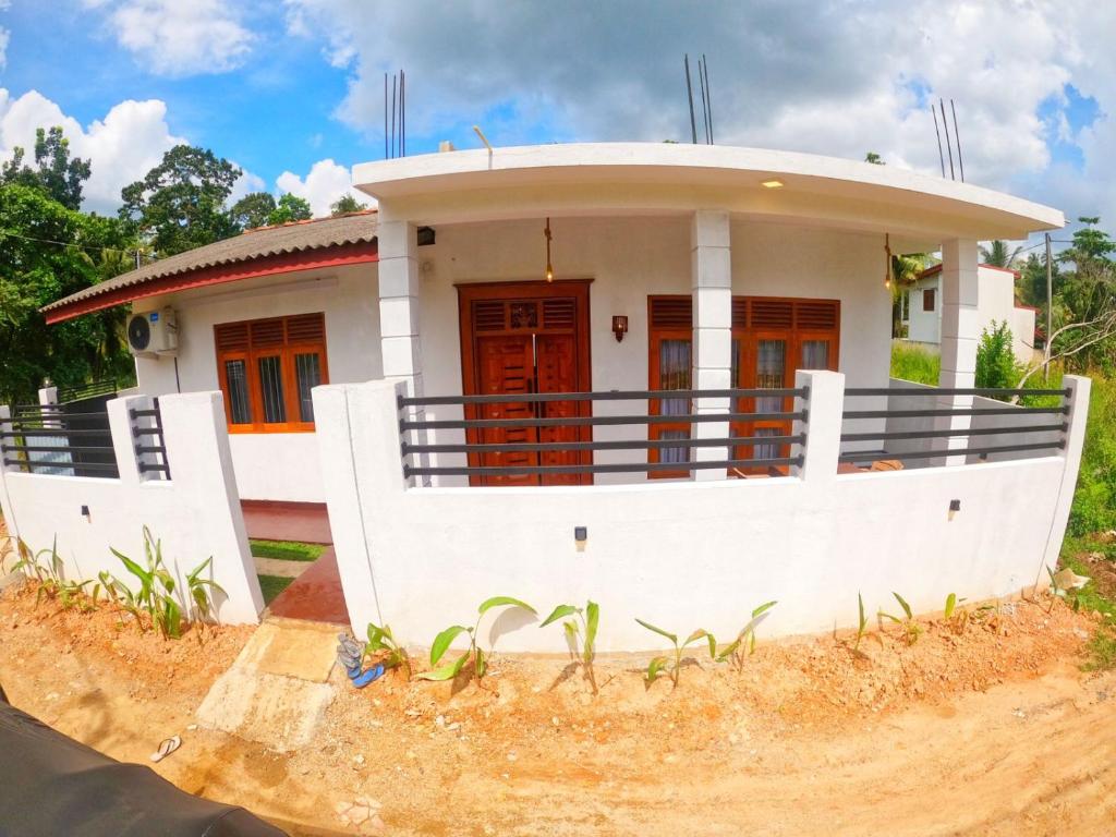 una pequeña casa blanca con una puerta roja en Thushen Villa, en Matara