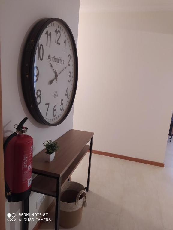 une horloge suspendue sur un mur à côté d'une table dans l'établissement Apartamento Quitéria - Funchal, à Funchal