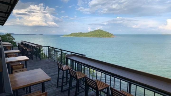 a balcony with tables and chairs and a view of the ocean at HEAVEN HILL LANTA in Ko Lanta