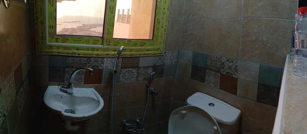 uma casa de banho com um lavatório, um WC e uma janela. em شقه عالبحر بجوار هيلتون عاءلات فقط em Alexandria
