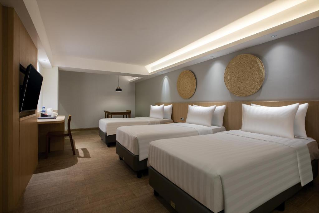 a hotel room with two beds and a television at Aveta Hotel Malioboro in Yogyakarta