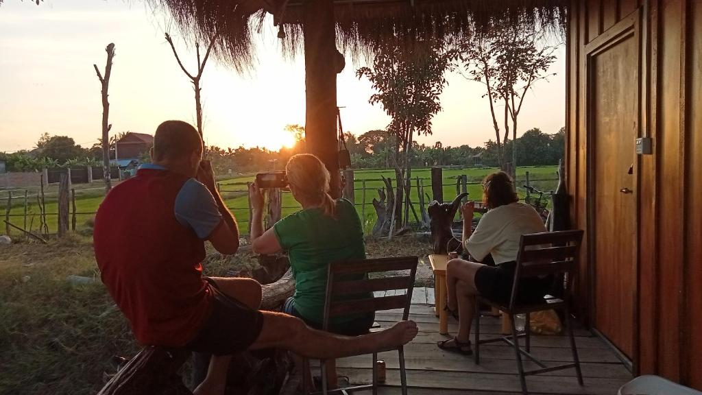 a group of people sitting on a porch watching the sunset at Meta Homestay in Phumĭ Puŏk Chăs