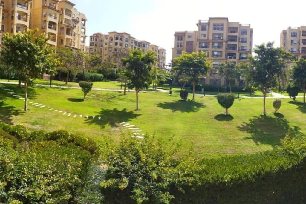 a park with trees and grass and buildings at Luxury Inn 3BR Amazing Garden view in Madinaty B1 in Madinaty