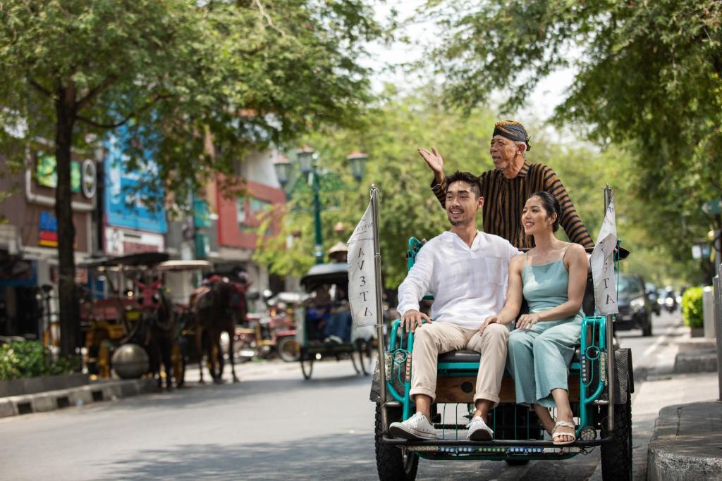 a man and a woman riding in a horse drawn carriage at Aveta Hotel Malioboro in Yogyakarta