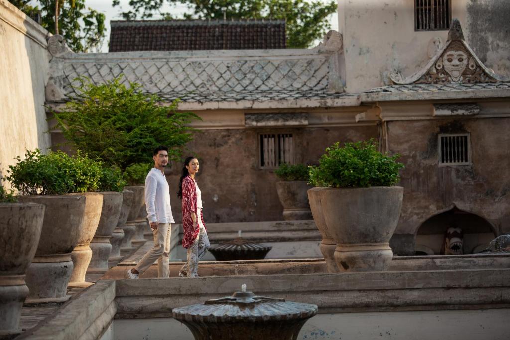 a man and woman walking down the steps of a building at Aveta Hotel Malioboro in Yogyakarta