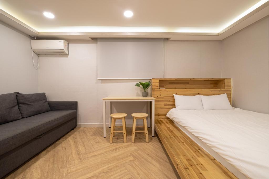 um pequeno quarto com uma cama e um sofá em Woody Two Bedroom In Hongdae em Seul