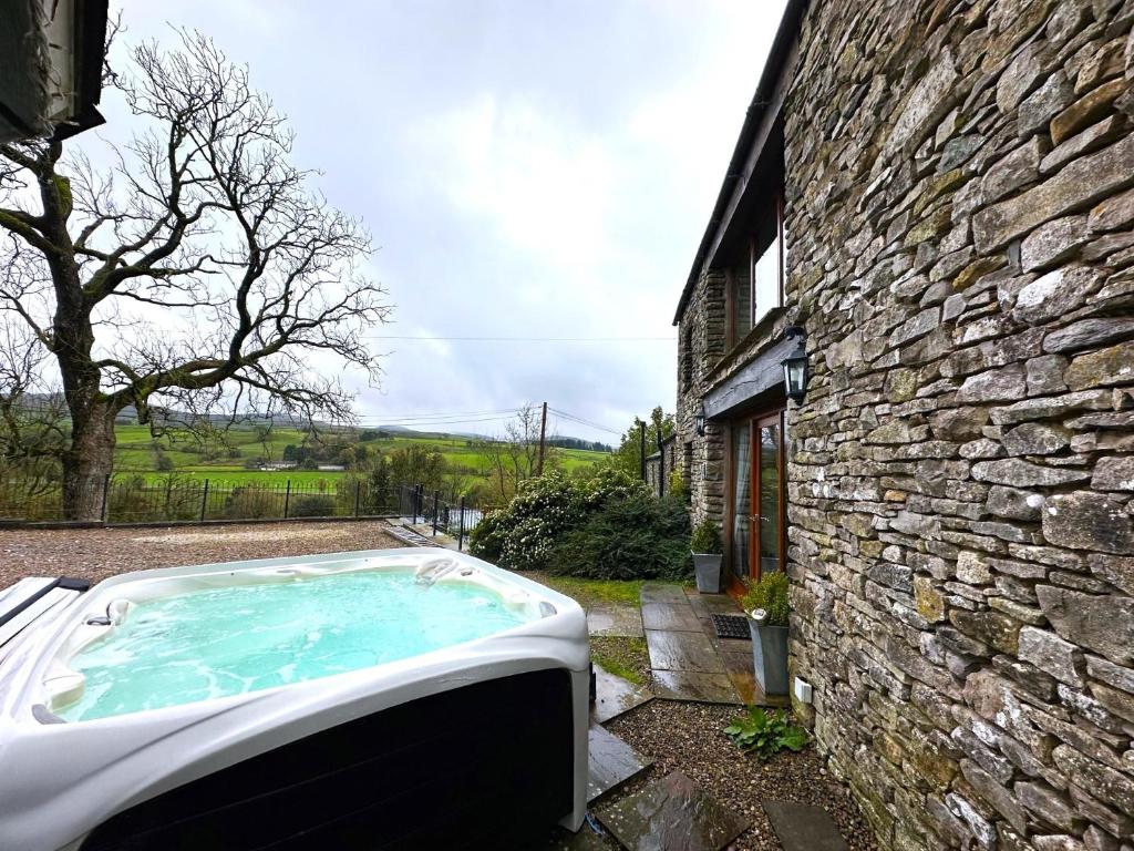 a hot tub in front of a stone building at 2 Bed in Kirkby Stephen 65635 in Orton